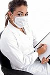Sitting Doctor With Mask On Her Mouth And Writing Board Stock Photo
