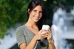 Smiling Beautiful Woman Texting With Her Phone In The Garden Stock Photo