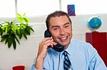 Smiling Executive Attending Call Stock Photo