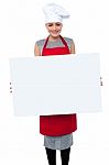 Smiling Female Chef Holding An Ad Board Stock Photo