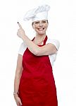 Smiling Female Cook Pointing Up Stock Photo