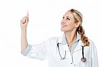 Smiling Female Doctor Pointing Upwards Stock Photo