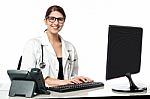 Smiling Female Doctor Working On Computer Stock Photo