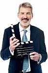 Smiling Man Showing A Clapperboard To The Camera Stock Photo