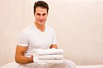 Smiling Young Man Holding Stack Of Towels Stock Photo