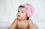 Sweet Newborn Baby In Pink Flower Hairband Lies On Bed Stock Photo