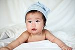 Sweet Newborn Baby In White Hat Lies On Bed Stock Photo