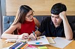 Teenage Boy And Girl Students, Doing Homework Together On A Note Stock Photo