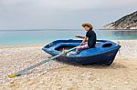 Teenage Boy Rowing In Boat On Greek Beach Stock Photo