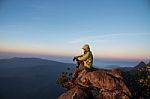 Thai Woman Sitting On Cliff Rock Enjoy Mountains View Stock Photo