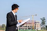 The Young Businessman Holds A Blueprint And Looks At The Structu Stock Photo