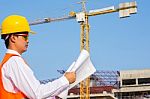 The Young Engineer Holds The Blueprint Over Building Being Built Stock Photo