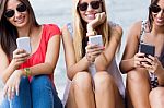 Three Girls Chatting With Their Smartphones At The Campus Stock Photo
