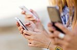 Three Girls Chatting With Their Smartphones At The Campus Stock Photo