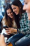 Three Young Woman Using Mobile Phone At Cafe Shop Stock Photo