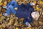 Toddler Blond Boy With Blue Eyes Lays On Bed Of Autumn Fallen Le Stock Photo