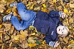 Toddler Blond Boy With Blue Eyes Lays On Bed Of Autumn Fallen Le Stock Photo