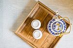 Top Of Traditional White Cup Of Tea And Teapot In Wooden Tray Closeup On Table Stock Photo