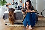 Two Beautiful Young Woman Using Mobile Phone At Home Stock Photo