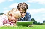 Two Children Lying Down And Using Tablet Pc Stock Photo