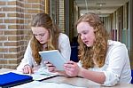 Two Dutch Teenage Girls Studying In Long School Corridor Stock Photo