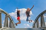 Two Happy Teenage Girls Jumping On Bridge Stock Photo