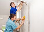 Two Workers Smoothing Wallpaper Stock Photo