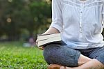 Woman Holding Book And Sitting In Park Stock Photo