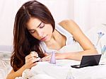 Woman In Bed Applying Nail Polish Stock Photo