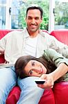 Woman Lying On Boyfriend's Lap While Using Remote Control Stock Photo