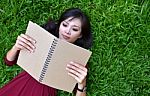 Woman Lying On Green Grass With  Book Stock Photo