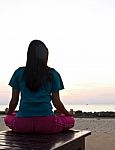 Woman Meditating On The Beach At Sunset Stock Photo