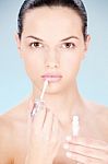Woman Putting Lipstick On Her Lips Stock Photo