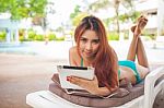 Woman Relaxing On Sunbed With Tablet Stock Photo