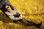 Woman Sit On Ground Be Filled With Leaves Of Ginkgo Tree In Fall Stock Photo