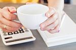 Woman's Hands Holding Coffee Cup With Calculator Background Stock Photo