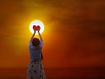 Women Gently Hold Red Heart To The Sun Stock Photo