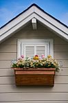 Wooden Window With Flower At The Roof Of The House Stock Photo