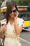 Young Brunette Laughs Into Phone On Street Stock Photo