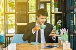 Young Businessmen Are Looking At Mobile Phones And Holding A Cup Stock Photo