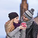 Young Couple In Love Embracing And Drinking Hot Drink From Red C Stock Photo