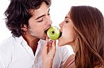 Young Couple Playfully Biting Green Apple Stock Photo