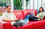 Young Couple Using Digital Tablet And Laptop On Sofa Stock Photo