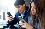 Young Couple Using Mobile Phone In Cafe Stock Photo