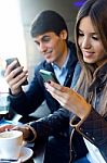 Young Couple Using Mobile Phone In Cafe Stock Photo