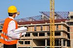 Young Engineer In Orange Shirt Stands Pointing At A Building Bei Stock Photo