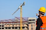 Young Engineer In Orange Shirt Stands Pointing At A Building Bei Stock Photo