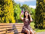 Young Girl Making Selfie Sitting On A Park Bench Stock Photo