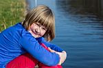 Young Girl Sitting At Waterfront Stock Photo