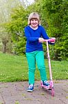 Young Girl Standing With Pink Scooter Stock Photo